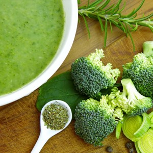 Bowl of green soup with green vegetables next to it