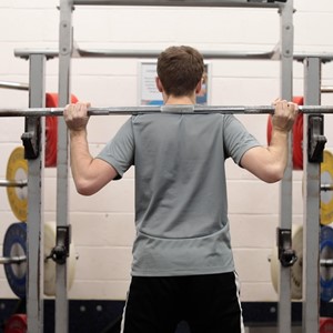 Student doing weight training with a bar